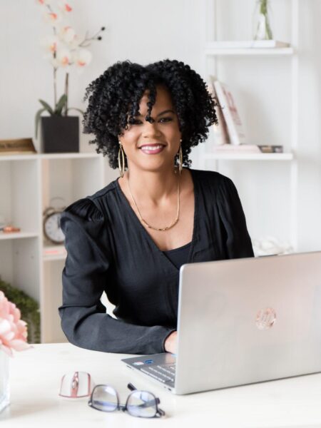 Operations Management Company owner, Danielle sitting at desk in a black shirt. Eliminating a business bottleneck.