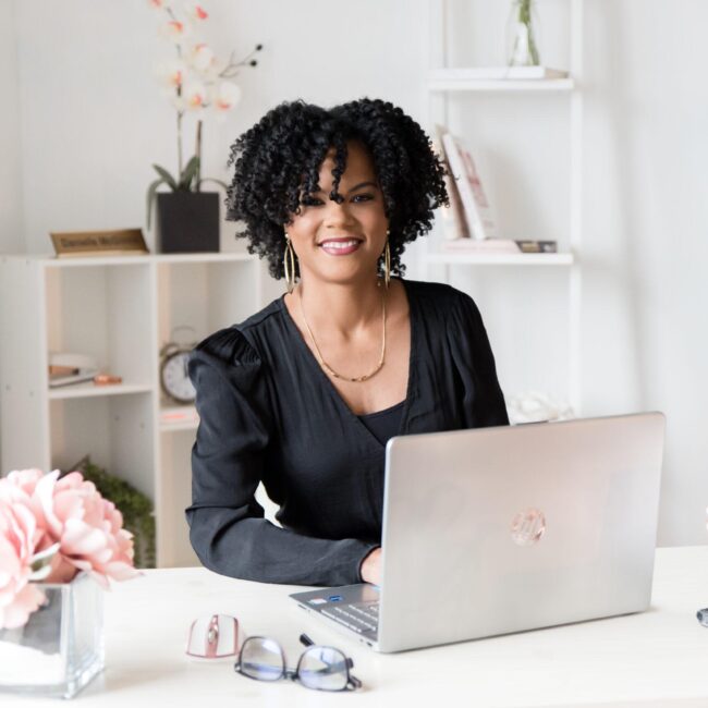 Operations Management Company owner, Danielle sitting at desk in a black shirt. Eliminating a business bottleneck.